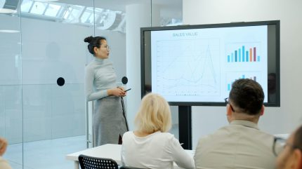 Presenter showing a sales performance chart to colleagues in a meeting room